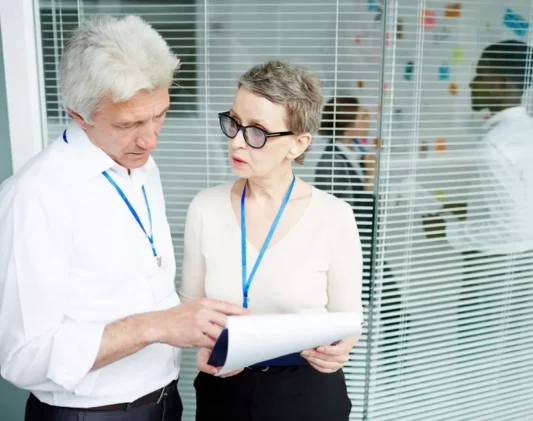 Healthcare professionals discussing documents in an office, highlighting the importance of understanding credentialing vs contracting in healthcare.