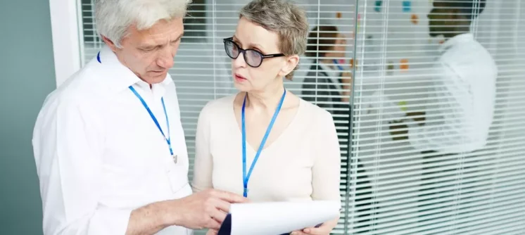 Healthcare professionals discussing documents in an office, highlighting the importance of understanding credentialing vs contracting in healthcare.