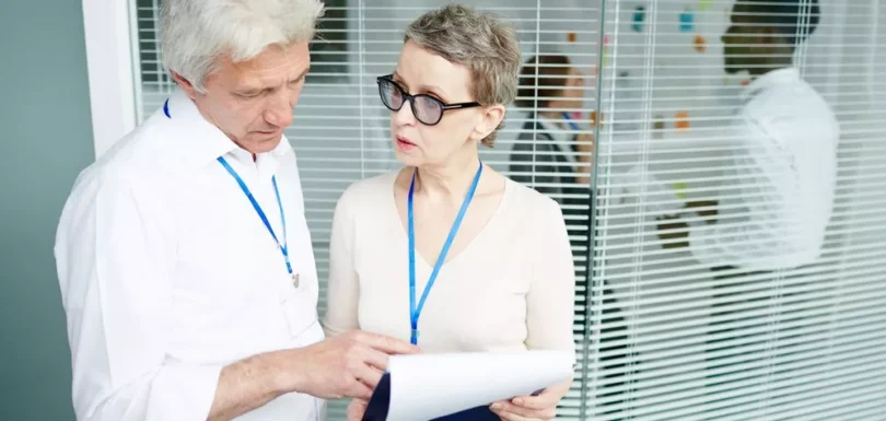 Healthcare professionals discussing documents in an office, highlighting the importance of understanding credentialing vs contracting in healthcare.